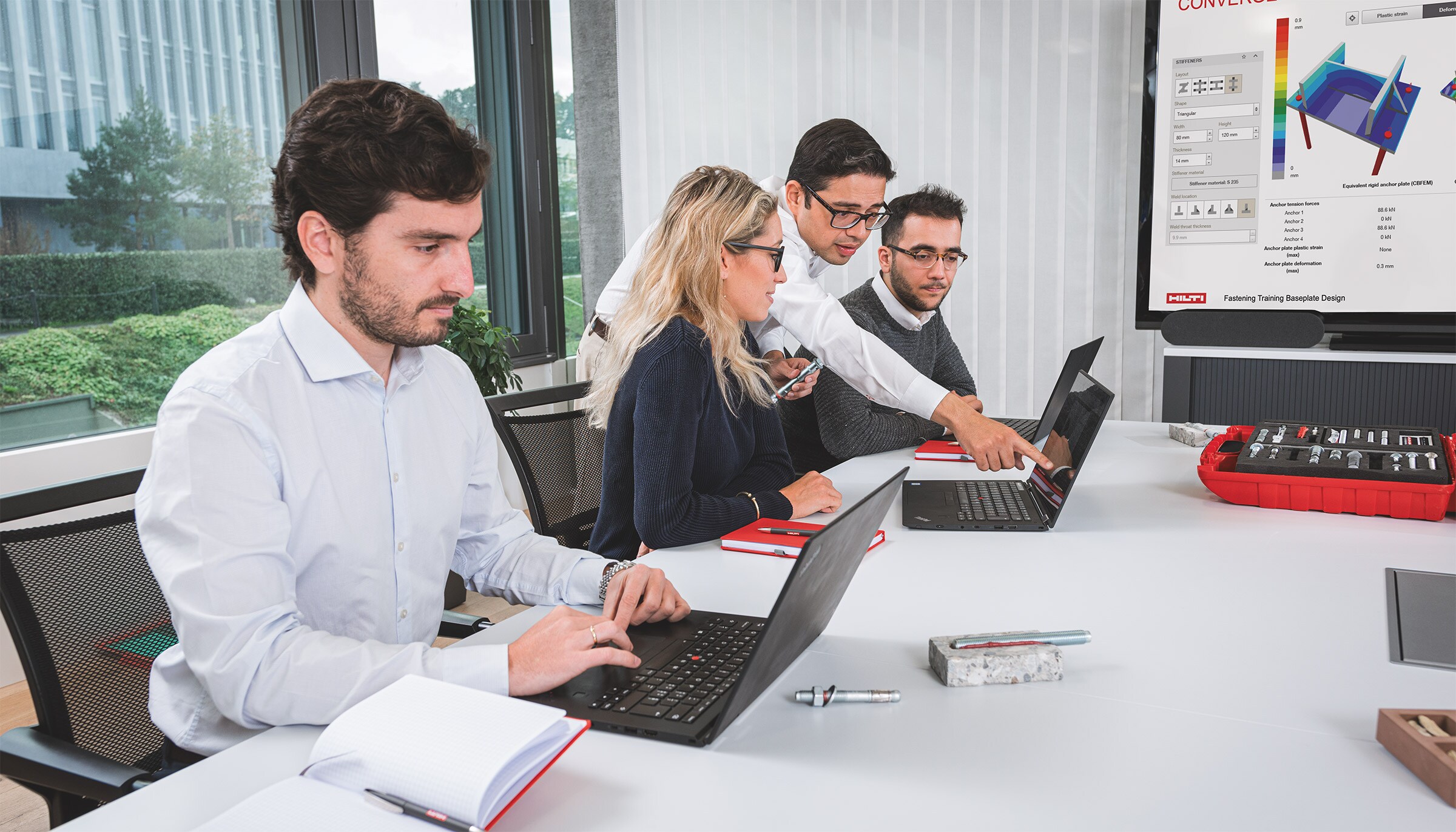 3 hommes et 1 femme travaillent devant leurs ordinateurs portables dans un bureau
