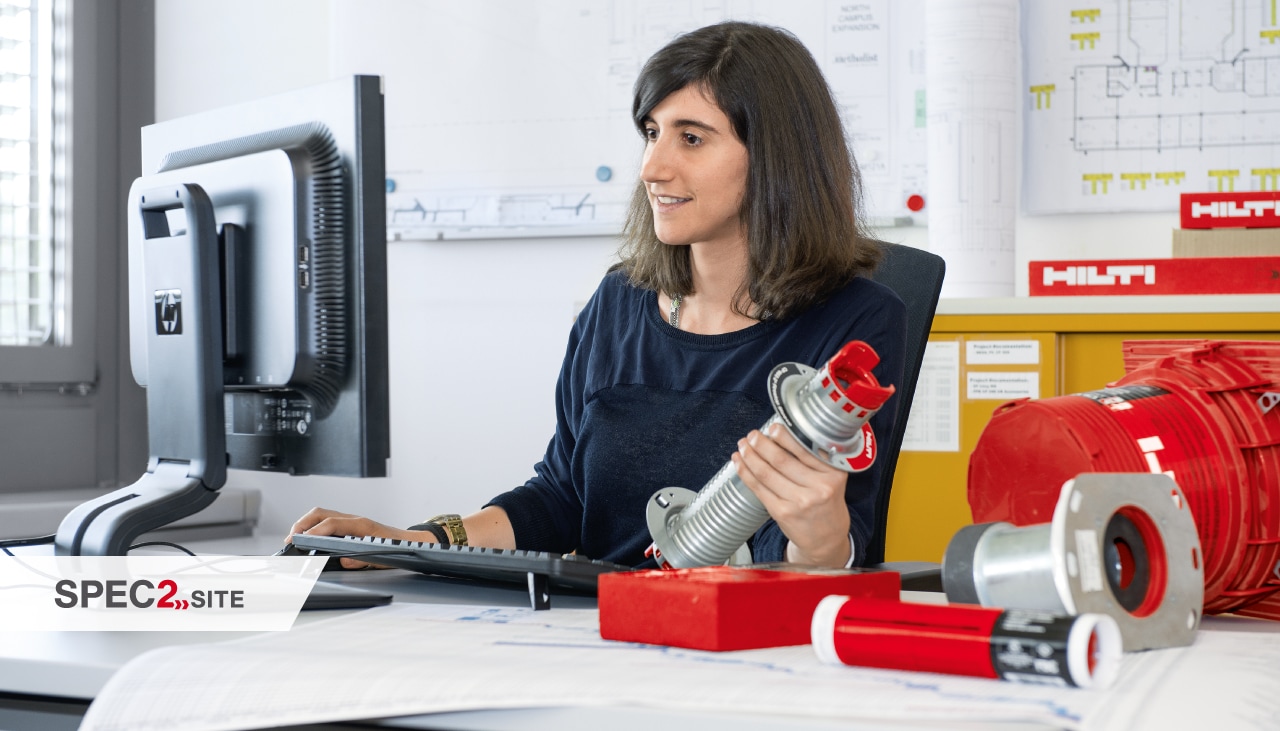 an engineer holds a firestopping solution while looking at a computer screen