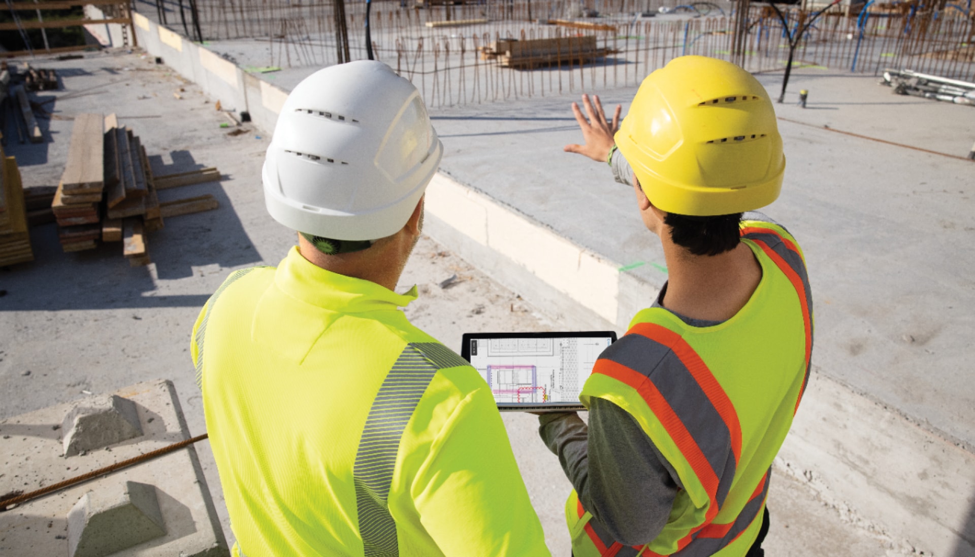 Deux hommes sur un chantier tiennent une tablette avec l'application de gestion de chantier Fieldwire by Hilti 