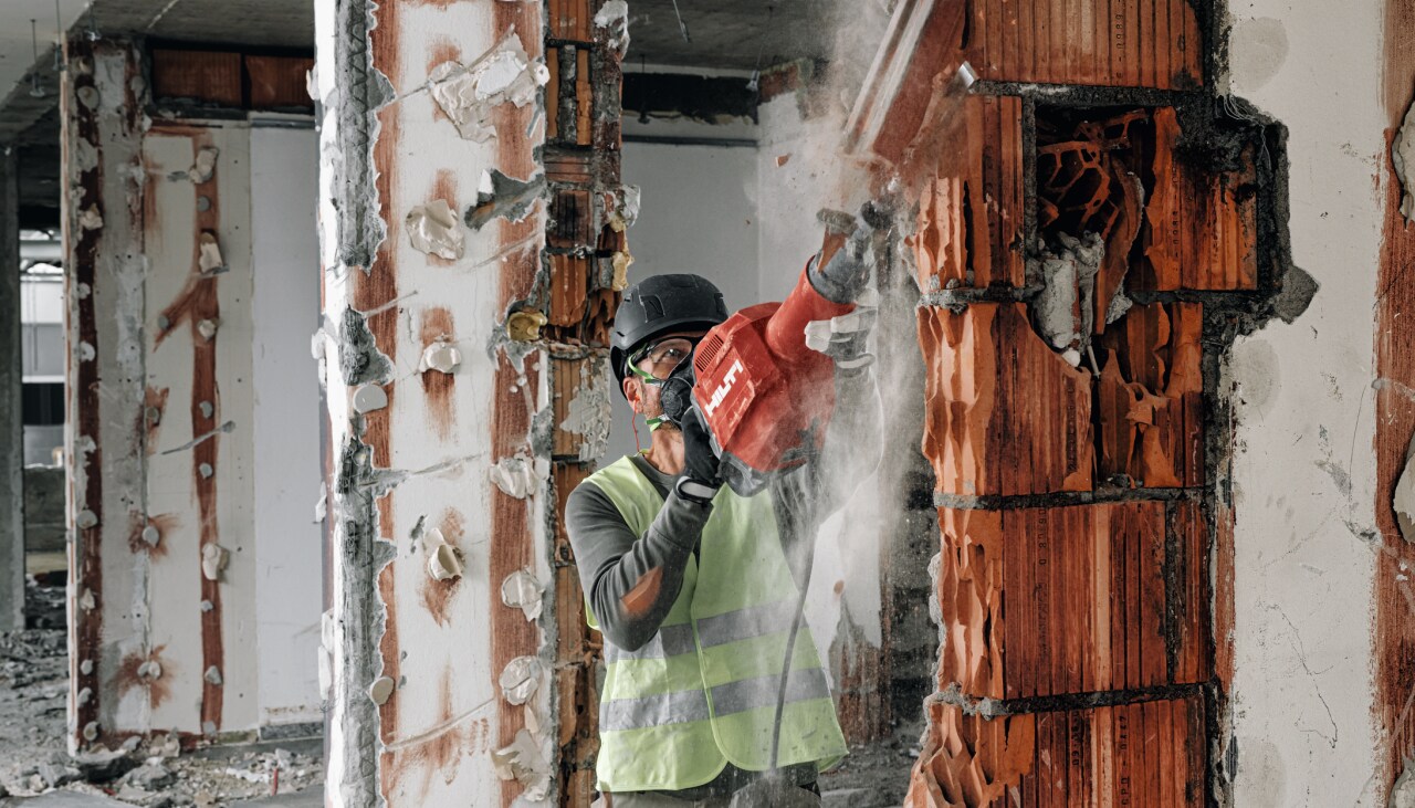 Un maçon abat un mur sur un chantier