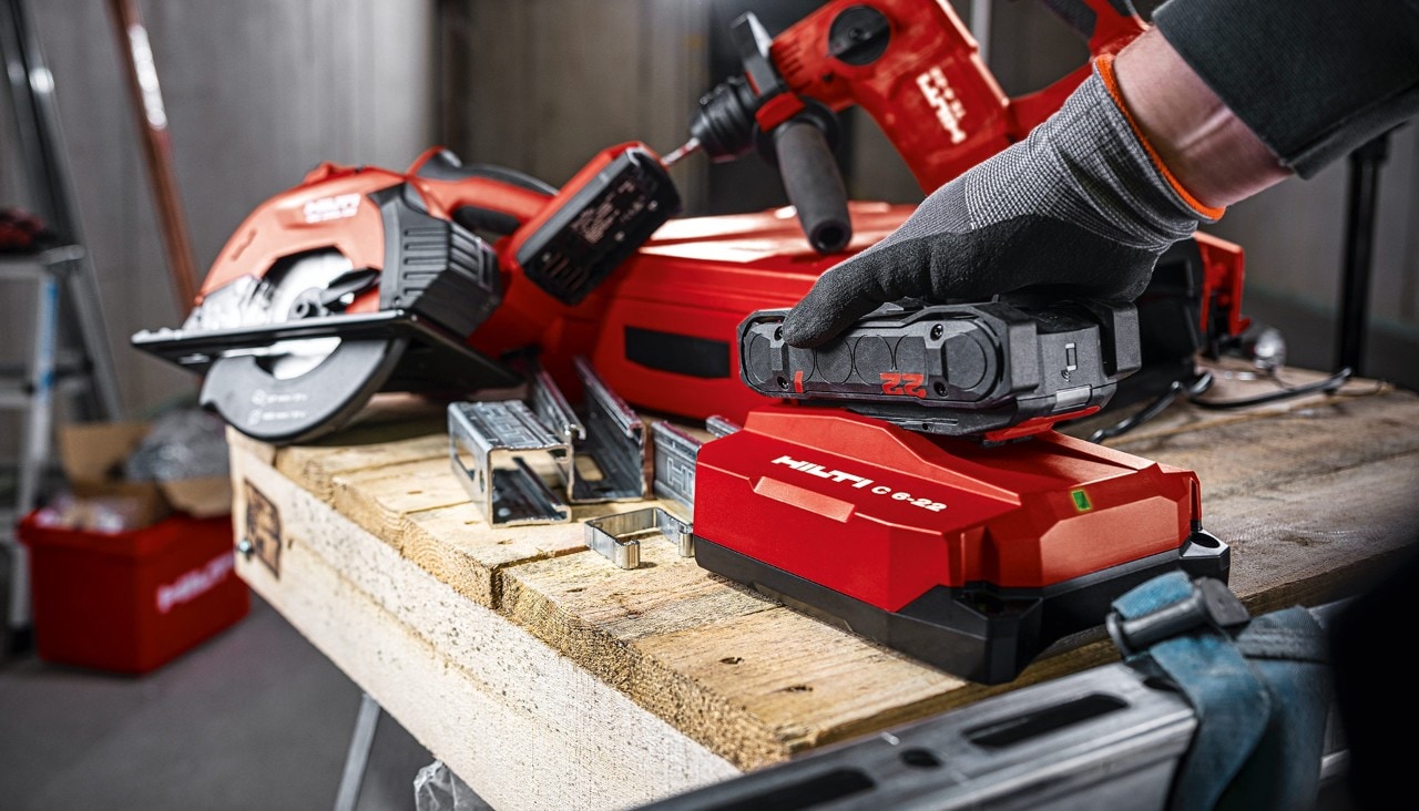 Une main insérant une batterie Hilti dans le chargeur
