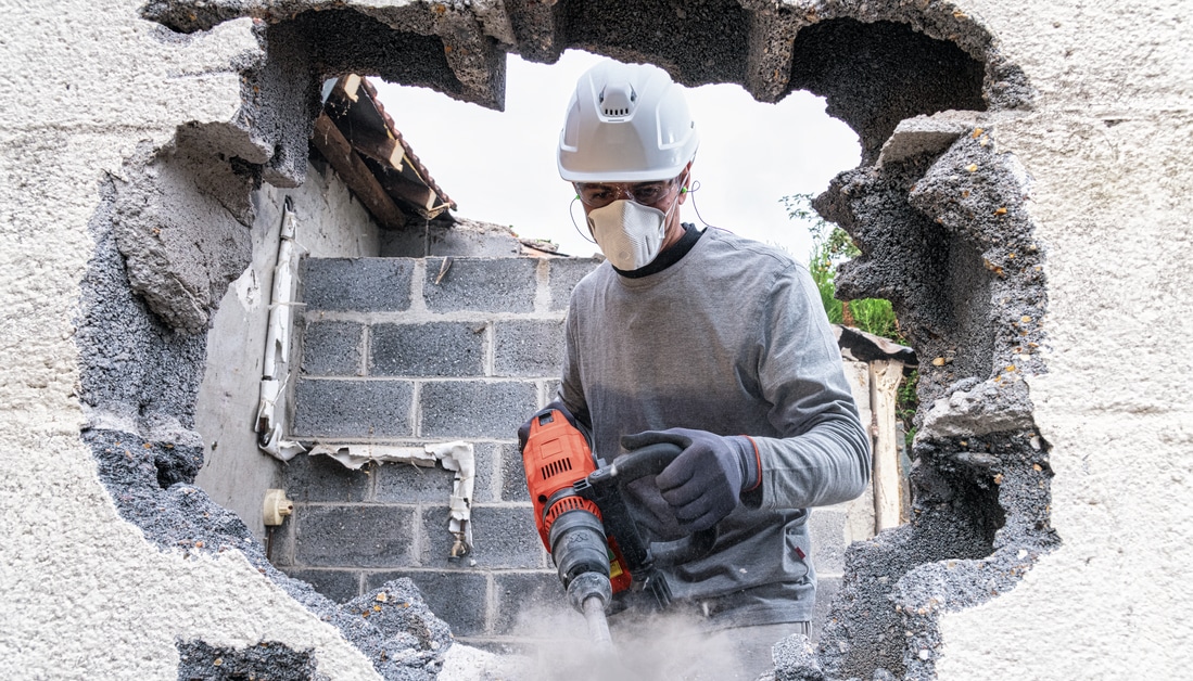 Un ouvrier démolit un mur en béton sur un chantier