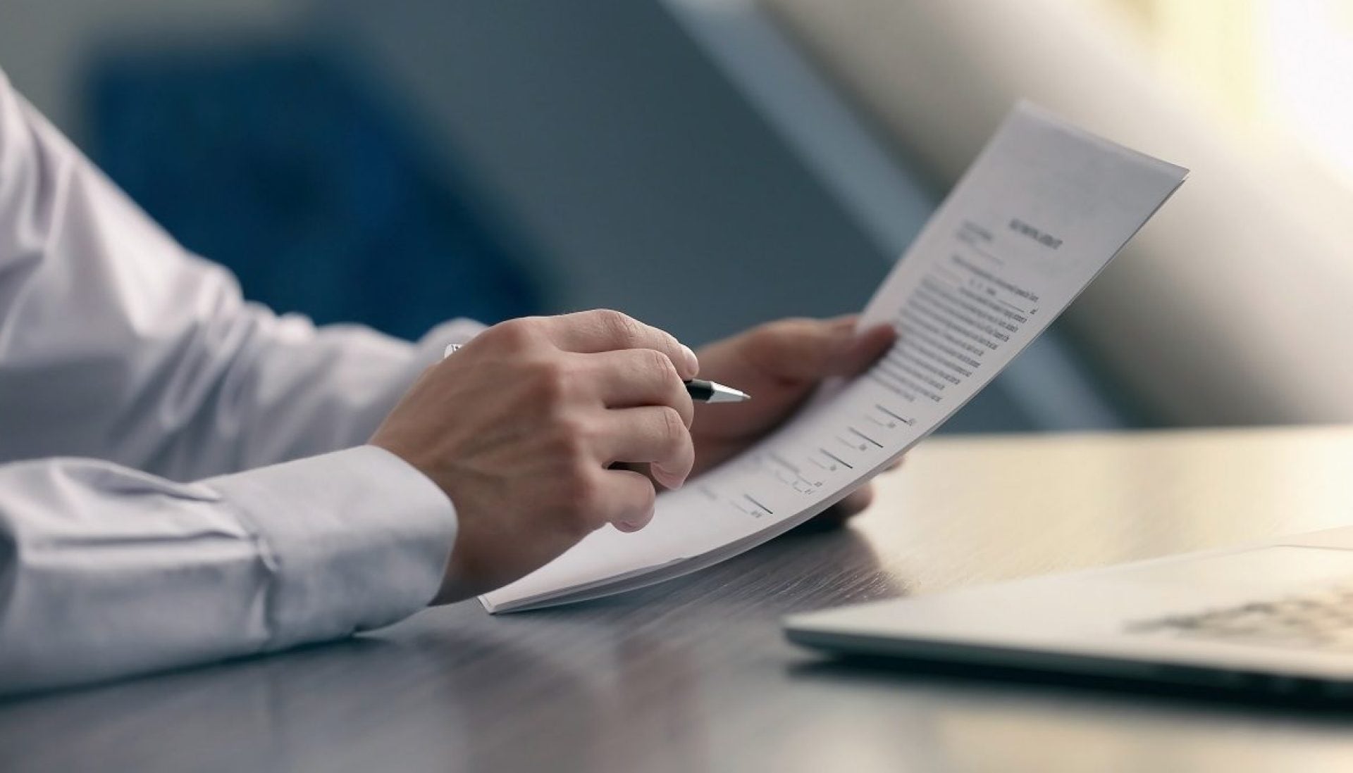 Un homme assis à un bureau tient un document dans sa main
