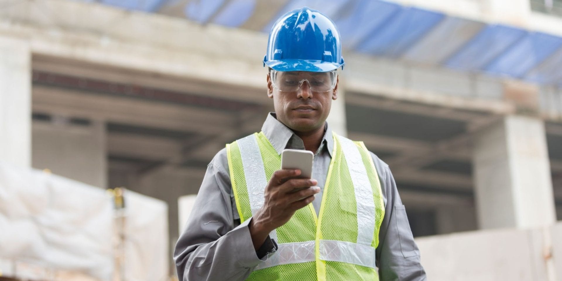 Un homme sur chantier tient un smartphone dans sa main